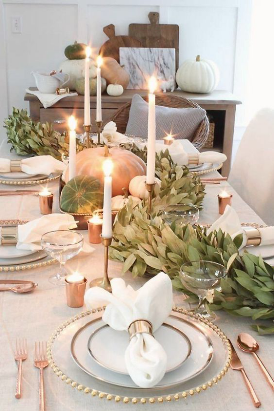 Podzimní dekorace stolu s dýní, sváteční stůl, bílé svíčky, zelené listy, krásné příbory, spousta lesku