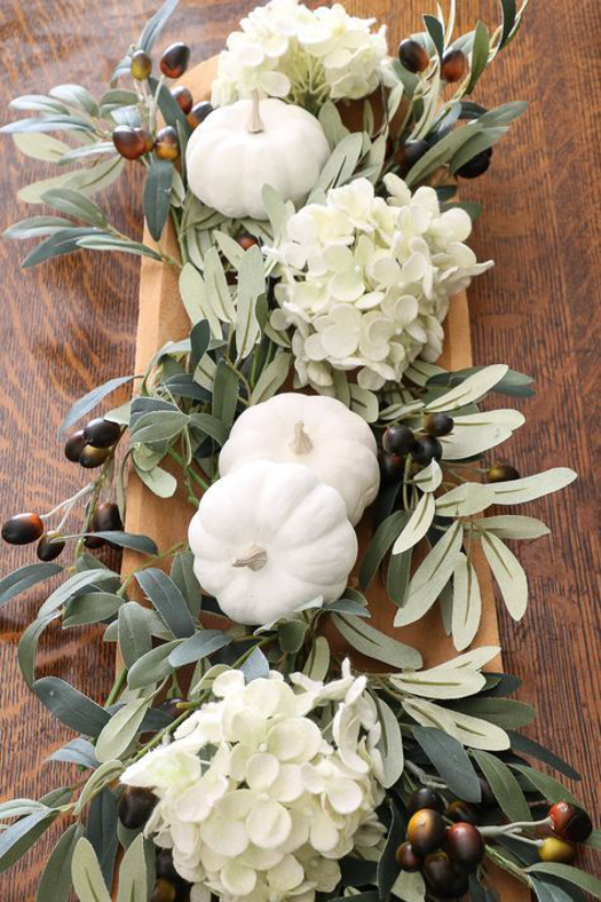Podzimní dekorace stolu s dýní bílé tykve na dřevěných podnosech hortenzie zelené listy žaludy
