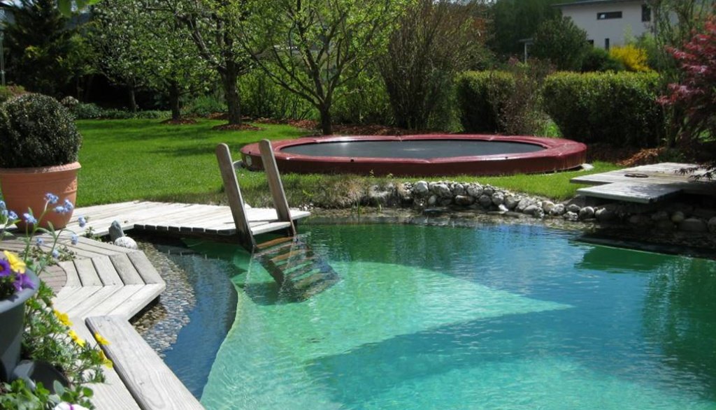 Stor gulvtrampoline rundt hagen med basseng
