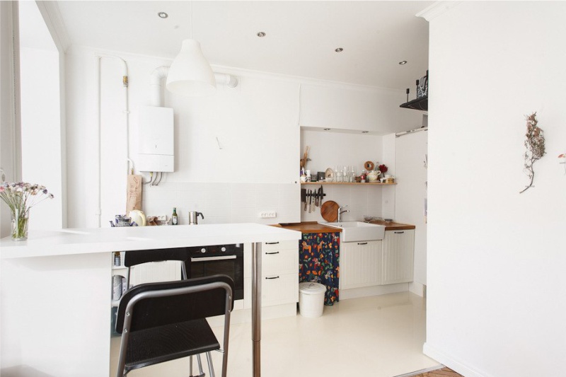 Dujinis vandens šildytuvas virtuvės interjere su baltomis sienomis