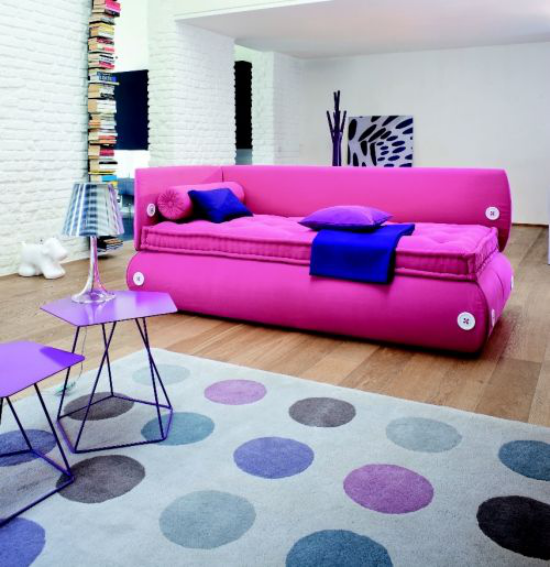 ekstravagante sofaer fancy modell i rosa marineblått kastet teppe bordlampe blekner i bakgrunnen