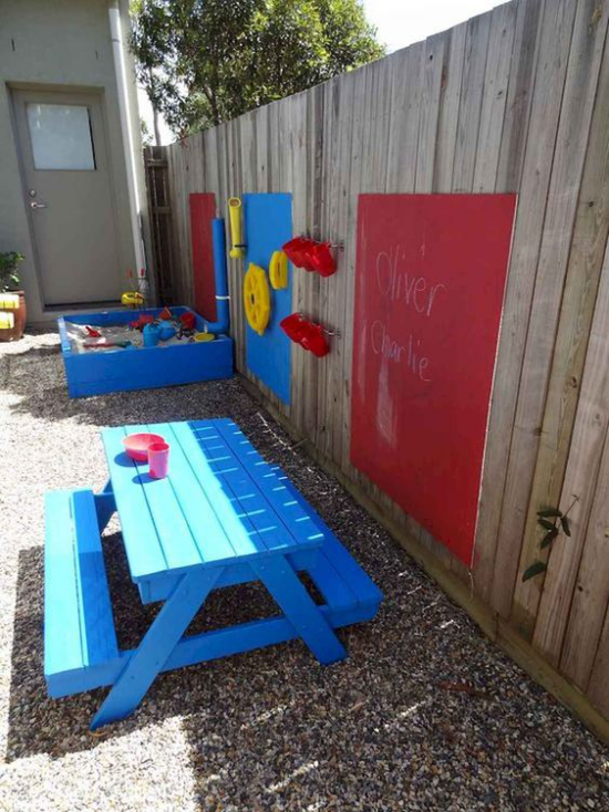 מגרשי משחקים לילדים בגינה משלהם, בור חול בצל חלקי, ספסל, לוח גיר אדום על הגדר