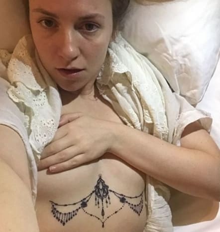 (Nuotrauka: Lena Dunham/„Instagram“) Naujausia „Dunham“ tatuiruotė atrodo kaip nuolatinis kūno papuošalas, o krūtinės centre įtvirtintas puošnus į sagutę panašus gabalas, o po kiekviena jos krūtine tęsiasi karoliukai, dekoratyvinė grandinė. „Dunham“ savo naują krūtinės tatuiruotę debiutavo „Instagram“, parašydama asmenukę be marškinėlių: „Ačiū @trinegrimm už mano kario krūtinės lėkštę/zylės liustra“. Dunham „Instagram“ antraštėje pažymi, kad ši „zylės liustra“ yra pirmasis originalus jos tatuiruočių meistrės kūrinys, kuris, jos teigimu, jaučiasi „šventas ir kietas“, ir dėkoja Grimmui už tai, kad ji „neslėpė“, kad nukopijavo Rihannos tatuiruotės vietą.