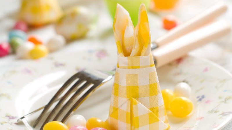מפיות צהובות מקפלות ארנב פסחא על שולחן החגיגה המאושר
