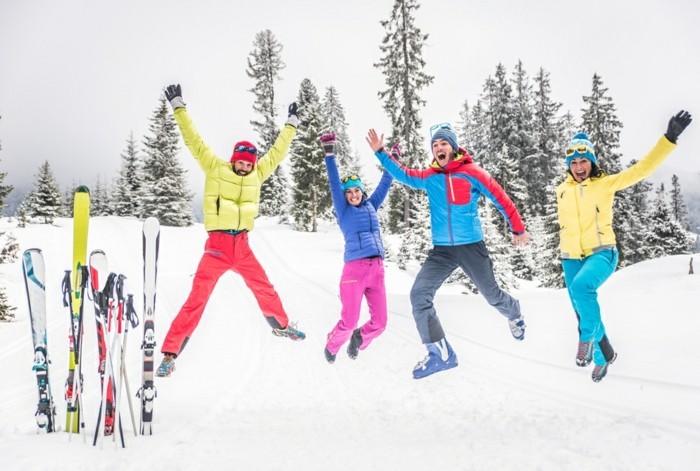 משפחה בת ארבע קופצות משמחה על מדרון סקי