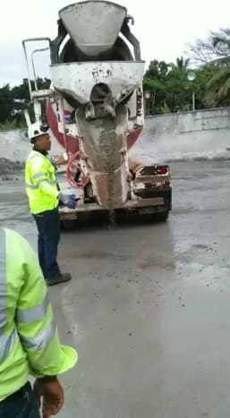 Du darbuotojai kantriai laukia, kol viskas, kas užkemša cemento lataką, išsivalo.