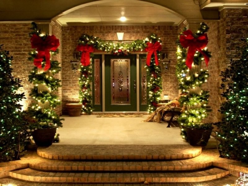 Julepynt utenfor inngangen til huset grener røde bånd