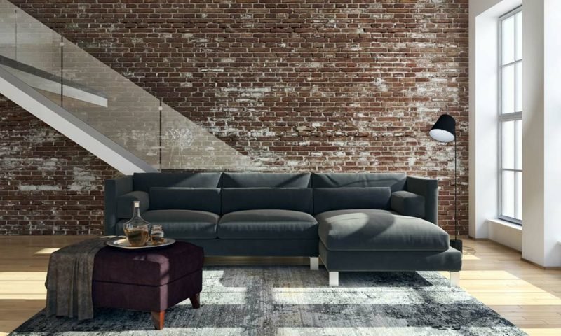 Obývací pokoj ve tvaru dlouhé pohovky šedé čalounění cihlová zeď